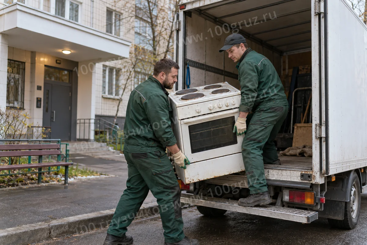 Грузчики загружают старую отдельно стоящую электроплиту в фургон