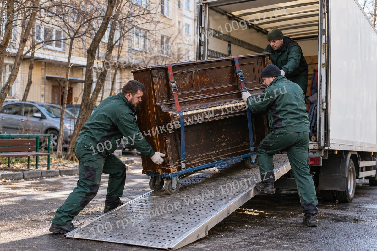Грузчики закатывают старое пианино на тележке по трапу в фургон